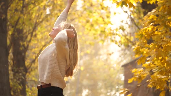 Fall outdoor. Fashionable lovable blonde woman dance laughing in autumn park. Beautiful Carefree gir