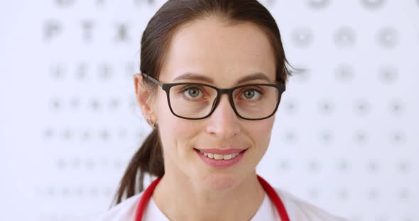 Portrait of Woman Ophthalmologist in Glasses on Background of Eye Examination Table Movie Slow