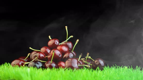 Pile of Vibrant Cherries on Green Grass Against Black Background