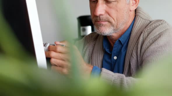 Male executive holding digital camera at desk