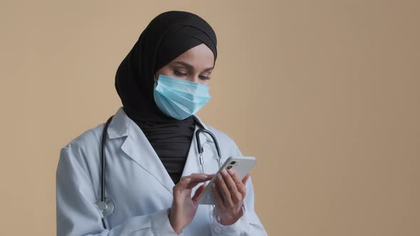 Muslim Masked Female Doctor Therapist Wear Hijab White Coat Holding Mobile Use Smartphone Medical