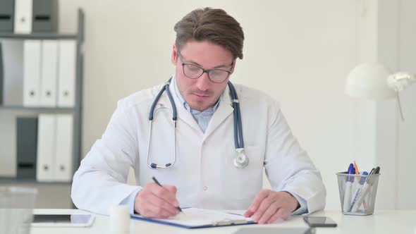 Middle Aged Male Doctor Writing on Paper