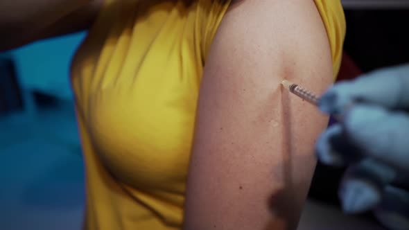 Injection with a syringe in the arm.  Doctor injects a coronavirus vaccine into a woman patient.