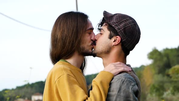 Happy gay couple hugging and kissing in nature