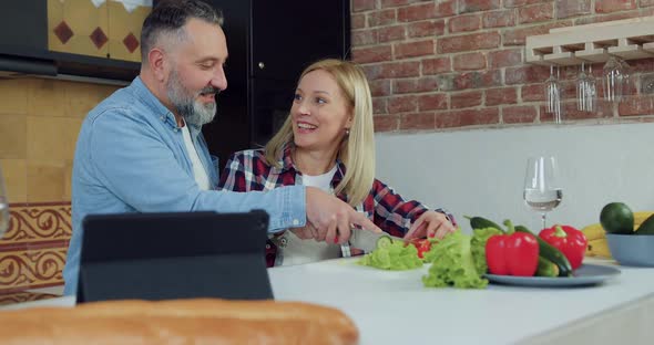 Woman and Her Handsome Joyful Bearded Husband Cutting Together Pepper During Preparing dinner