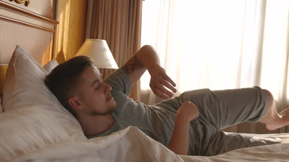 Handsome Man Waking Up Stretch Oneself and Opening the Window Curtain on a Sunny Morning in a Hotel