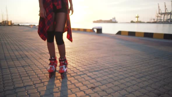 Young Stylish Funky Girl with Green Hair Riding Roller Skates and Dancing Near Sea Port During