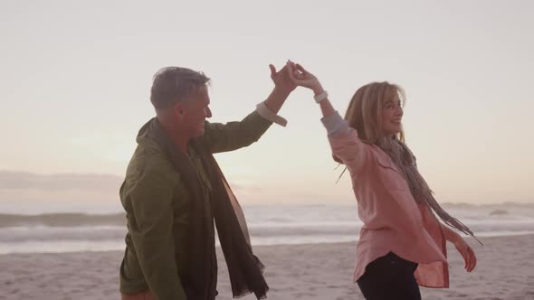 Active senior couple dancing on beach