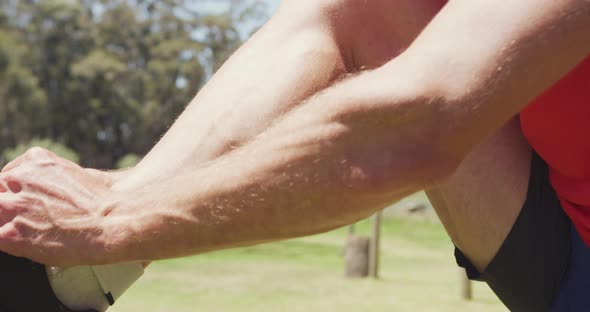 Fit caucasian man in sports clothes tying shoe sitting outdoors in the sun preparing for exercise