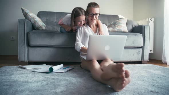 Young Woman and Her Daughter Looking at the Notebook Screen