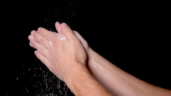 An athlete preparing for workout by clapping his hands for evenly distributing the chalk powder, iso