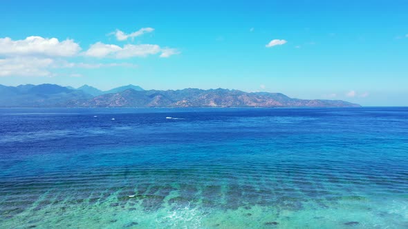 Tropical Paradise Of Coral Reefs Under The Crystal Clear Ocean Water With Mountains In The Backgroun