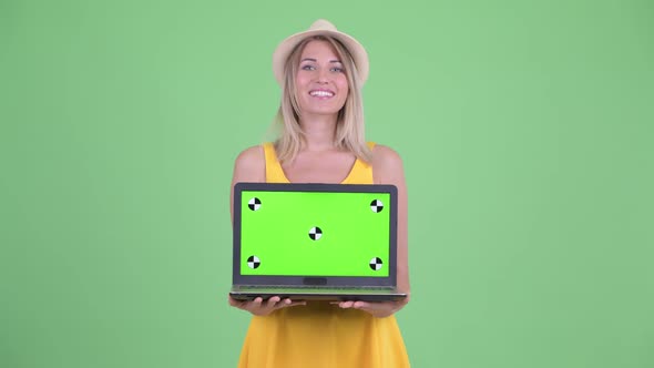 Happy Young Blonde Tourist Woman Talking While Showing Laptop