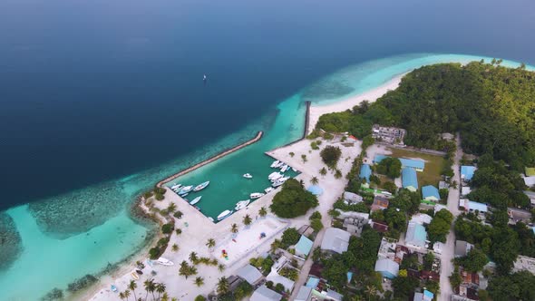 View of the blue lagoon with a marina for yachts and houses with blue roofs located on the Maldivian