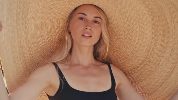 Beautiful Girl Wearing Big Straw Summer Hat on the Beach