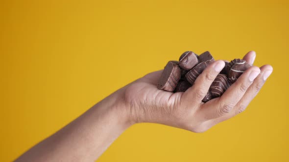 Holding Dark Chocolate Against Yellow Background