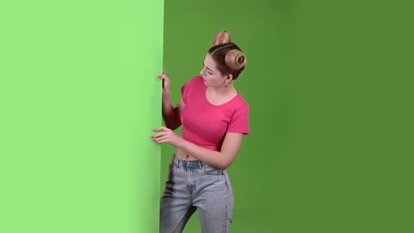 Teen Peeks Out From Behind a Green Board and Shows a Thumbs Down. Green Screen. Slow Motion