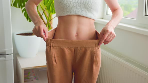 Close Up of a Female Slim Waist in Old Jeans After Successful Diet Indoors