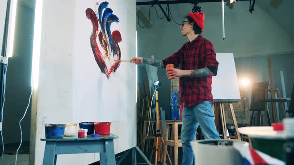 Art Studio with a Tattooed Man Sprinkling Paint on the Picture