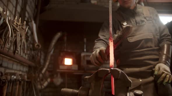 A Man Blacksmith Forging a Twisted Piece of Metal Put in the Clamps