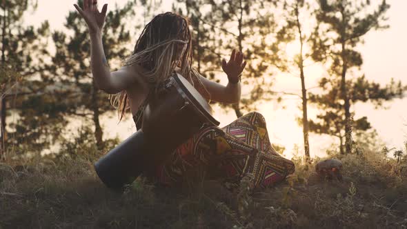 Beautiful Young Hippie Woman with Dreadlocks Playing on Djembe