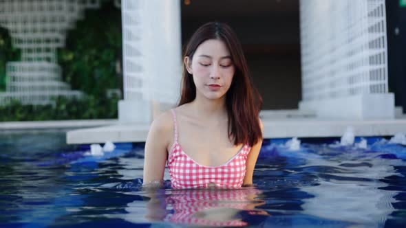 Asian young woman relax in swimming pool at luxury hotel spa