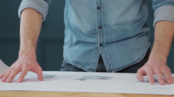 Close Up Shot of Young Man Hands Engineer Opening the Paper and Checking the Construction Drawings