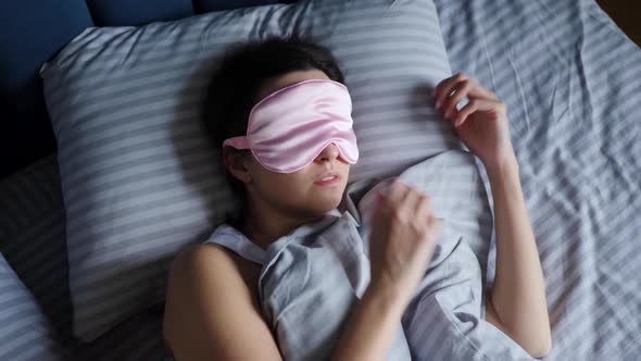 Woman in a Pink Eye Mask Lies Under a Blanket in a Bed and Suffers From Insomnia