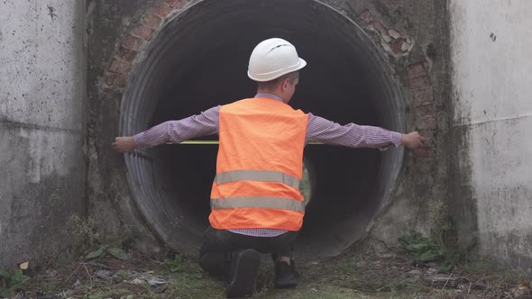 A builder engineer makes measurements of the structure of an underpass under the railway.
