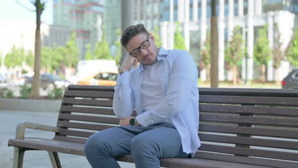 Tired Man Sleeping While Sitting Outdoor on Bench