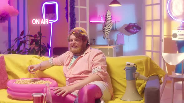 Man Eating Popcorn and Watching TV in Neon Room