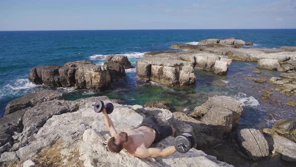 Young man working out with dumbbells outdoors.