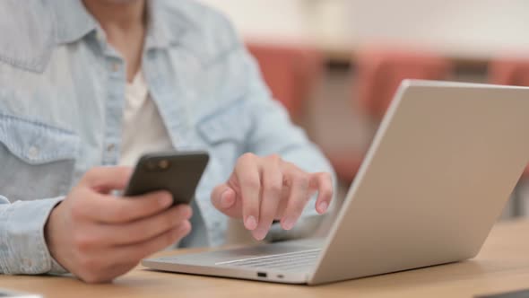 Male Hands Using Smartphone While Typing on Laptop Close Up