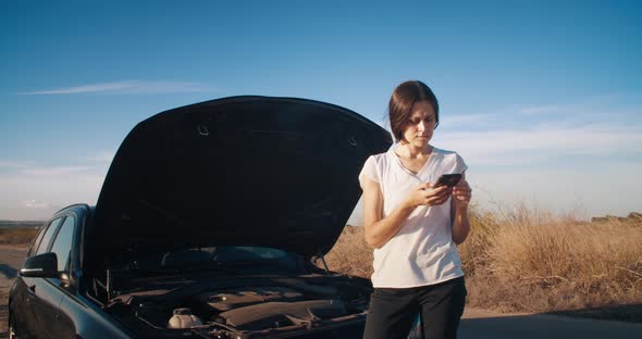 Young Woman in Front of Breakdown Car Using Smartphone Calling Service on Road