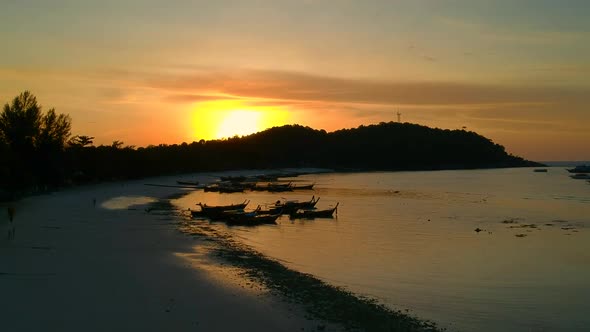 Aerial shot of beach during sunset with a Thai Boat