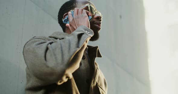 AfricanAmerican Man is Using a Mobile Phone While Walking in the City