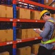 Asian man stocking up with barcodes on a box placed on a steel shelf in a warehouse. - VideoHive Item for Sale