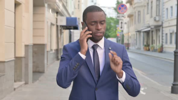 African Businessman Talking on Phone While Walking on Street