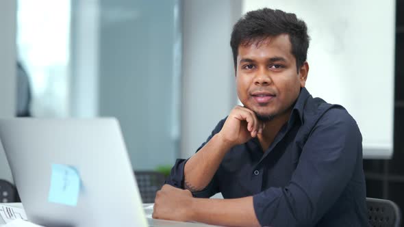 Portrait of Friendly African Male Sitting in Workplace at Modern Office Looking at Camera