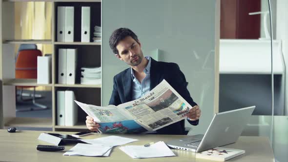 Businessman reading newspaper during break from work
