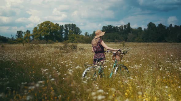 Tourist Girl Relaxing On Countryside Wildflower Field.Woman Cyclist Walking With Bike.