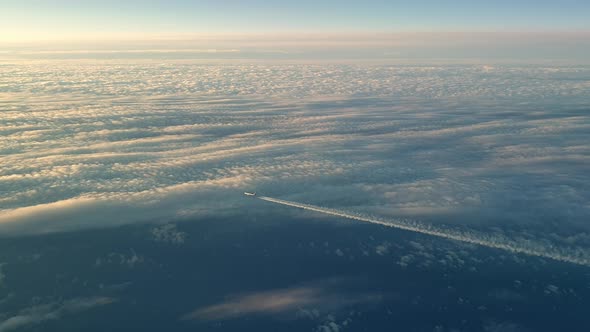 Incredible view from the cockpit of an airplane flying high above the clouds leaving a long white co