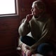 Woman in Old Age Sits By the Window and Looks Alone Into the Distance - VideoHive Item for Sale