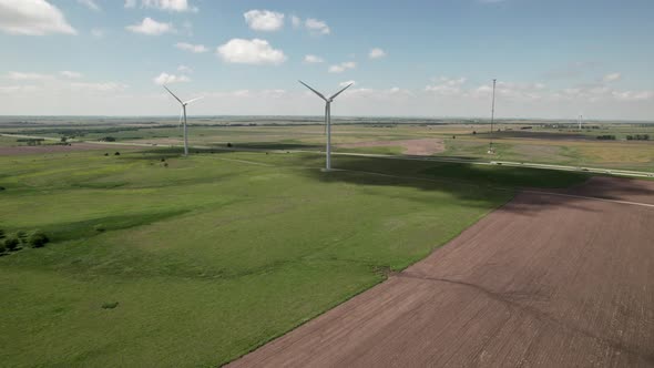 Turbines rotate slowly in wind as traffic travels on state highway Aerial turn.