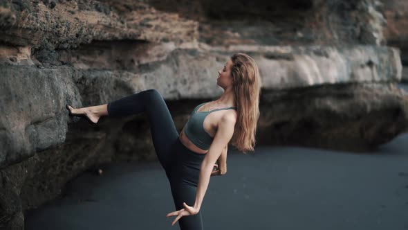 Woman Doing Stretching Exercises on Black Sand Beach Near Cliff Slow Motion