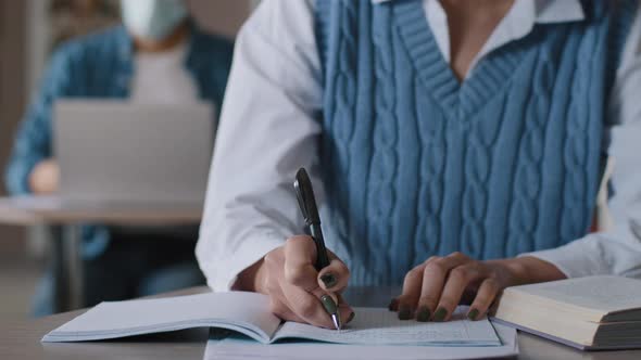 Closeup Unrecognizable Woman Student Sitting at Desk in Classroom Writes in Notebook Noting