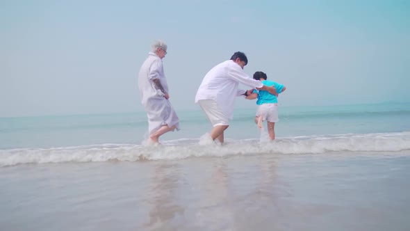 Grandfather and grandmother are playing with their little granddaughter on the beach.