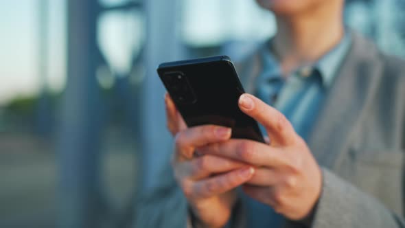 Woman in a Coat Walking Around the City in the Early Morning and Using Smartphone