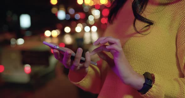 Woman's Hands which Using Her Smartphone in the Evening Among Lights of Night City