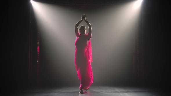 Silhouette a Young Girl Dancer in a Red Sari. Indian Folk Dance. Shot in a Dark Studio with Smoke